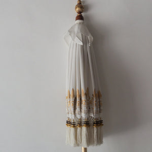 Hand-painted Balinese parasol in white with intricate golden motifs, showcasing traditional craftsmanship and unique design.