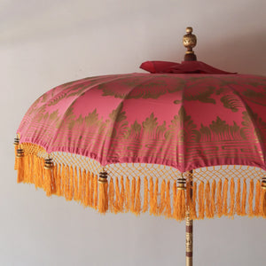 Balinese pink and gold hand-carved umbrella with yellow fringe and ornate patterns