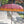 Handcrafted Balinese pink parasol with gold patterns and yellow fringe outdoors