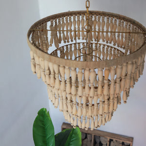 Handmade Balinese wood bead chandelier with natural finish, hanging in a bright room.