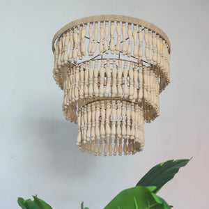 Handmade wooden bead chandelier with three tiers, hanging in a minimalist room