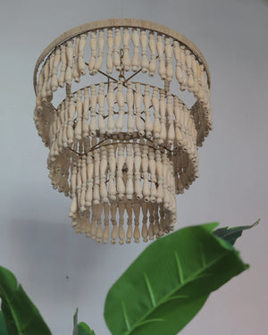 Handcrafted wooden bead chandelier with tiered design, tropical leaves in foreground