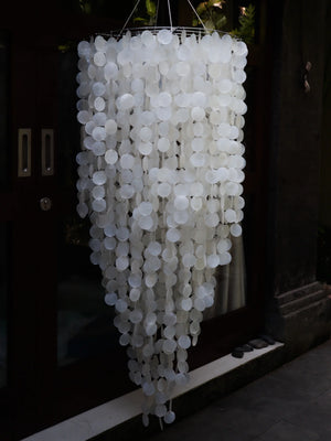 Handmade Balinese seashell chandelier with cascading white shell discs, outdoor setting