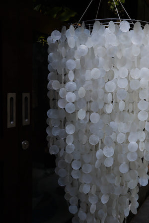 Handmade Balinese seashell chandelier with round white shell discs, hanging by a door