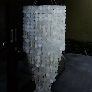 Handmade Balinese seashell chandelier with cascading white shell discs, outdoor setting