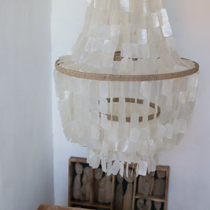Handmade Balinese seashell chandelier with cascading white shell pendants in a minimalist room