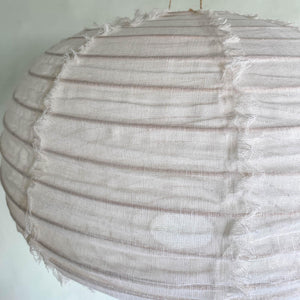 Close-up of a round handmade linen pendant lamp with textured, rustic seams