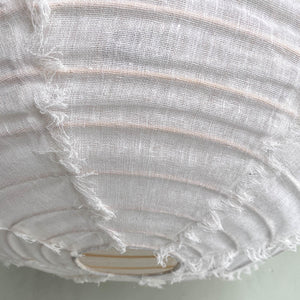 Close-up of handmade white linen lampshade with frayed edges and wooden frame.