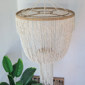 Handmade Balinese seashell chandelier with cascading beads, hanging in a bright room