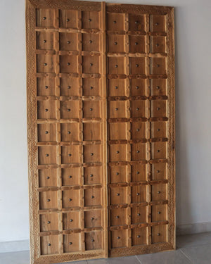 Hand-carved Balinese wooden double doors with geometric panels and intricate border design
