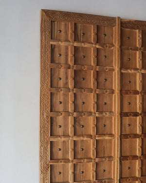 Hand-carved Balinese wooden door with geometric patterns and intricate border details