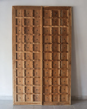 Hand-carved Balinese wooden door with decorative panel detailing and natural finish