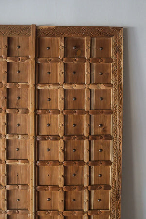 Hand-carved wooden door with geometric panels and intricate natural wood detailing