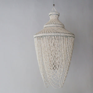 Handmade Balinese seashell chandelier with cascading beaded strands against a gray wall