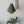 Handmade olive green pendant lamp with woven chair, carved wall art, and indoor plant