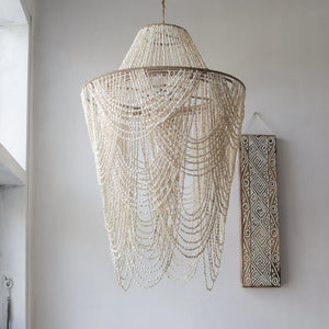 Handmade Balinese seashell chandelier with intricate draped design, hanging in a modern room