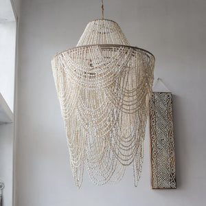 Handmade Balinese seashell chandelier with intricate bead strands, hanging in a modern room