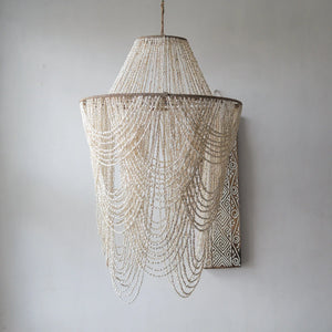 Handmade Balinese seashell chandelier with layered draped beads against a neutral wall
