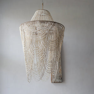 Handmade Balinese seashell chandelier with layered draped beads against a plain wall