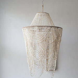 Handmade Balinese seashell chandelier with cascading beads against a neutral wall