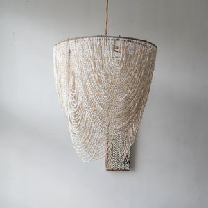 Handmade Balinese seashell chandelier with layered white shells against a plain wall