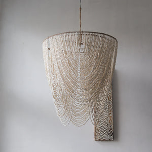Handmade Balinese seashell chandelier with cascading beads against a neutral wall