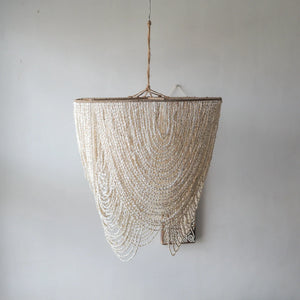 Handmade Balinese seashell chandelier with cascading strands against a plain wall