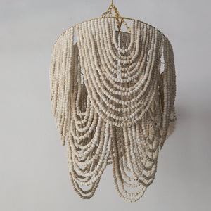 Beaded chandelier in gold and white, handcrafted in Bali, showcasing elegant draping design.