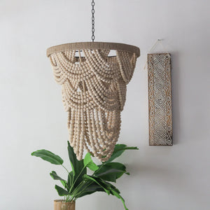 Handmade wooden bead chandelier with tropical plant and carved wall art in a modern room