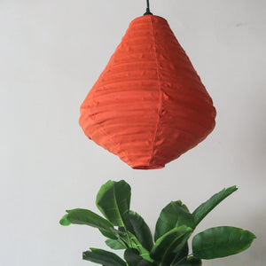 Handmade orange fabric pendant lamp with tropical green plant, minimalist home decor