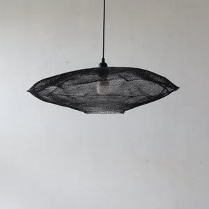 Handmade black mesh pendant light with unique organic shape against a neutral wall