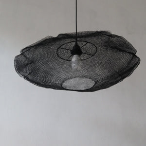 Modern handmade black mesh pendant light with exposed bulb against white wall