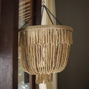 Handmade Balinese beaded chandelier with natural wood beads hanging by a window indoors