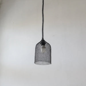 Handmade wire mesh pendant light with black woven design against plain white wall
