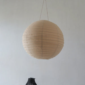 Handmade round beige paper lantern chandelier hanging against a plain wall