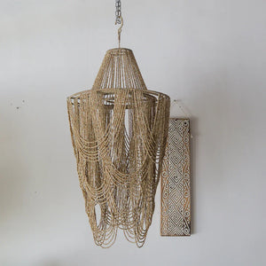 Handmade Balinese beaded chandelier with natural finish against a white wall