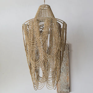 Handmade Balinese seashell chandelier with beaded strands on a neutral wall