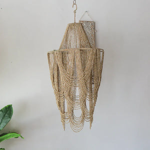 Handmade seashell chandelier with layered beads, boho decor, hanging against light wall