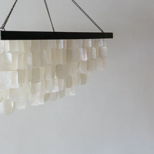 Rectangular seashell chandelier with layered white shell pieces, hanging from black frame