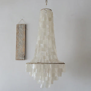 Handmade seashell chandelier with white geometric wall art on minimalist wall
