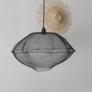 Black mesh pendant light with minimalist woven wall decor on a white background