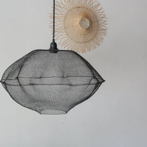 Black handwoven mesh pendant light with a modern boho design, hanging against a white wall.