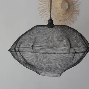 Black hand-woven mesh pendant light with minimalist modern design, hanging on a white wall