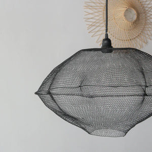 Black wire mesh pendant lamp with modern geometric design hanging against a white wall