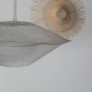 Modern wire mesh pendant light with organic, sculptural shape against white ceiling