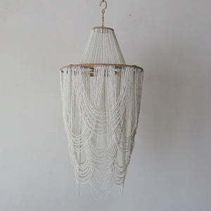 Handmade Balinese white seashell chandelier with cascading beaded strands on a neutral background