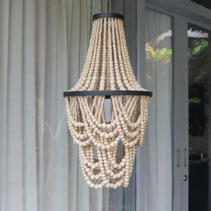 Handmade wooden bead chandelier with black metal frame, hanging outdoors by glass doors