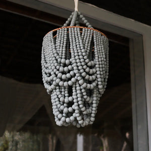 Handcrafted beaded chandelier with grey wooden beads hanging outdoors