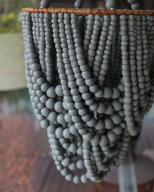 Close-up of handmade grey beaded chandelier with natural woven frame, Balinese decor.