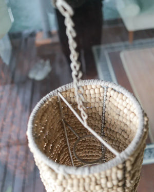 Handmade woven hanging basket with natural beads and rope, eco-friendly decor indoors